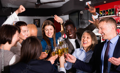International group of glad businesspeople toasting with champagne, having fun at office party in nightclub