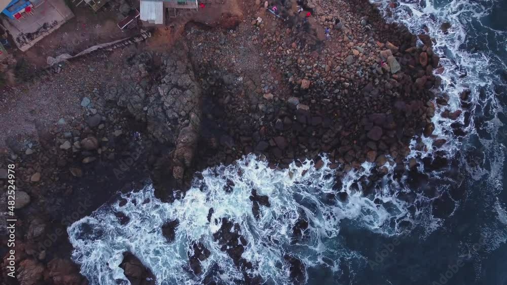 Olas rompen contra rocas en playa Los Molles, Chile, mientras personas observan el mar.