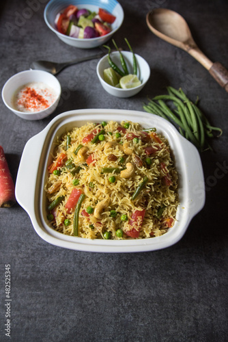 Homemade Indian lunch item pulao or vegetable fried rice or biryani served in a bowl. Top view.