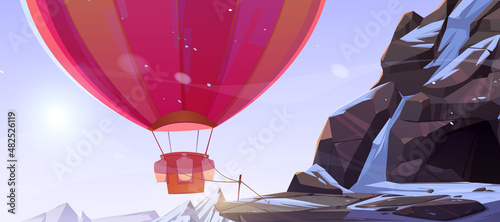 Hot air balloon tied near cave in mountains. Vector cartoon illustration of winter rocks landscape with stone cavern, snow and colorful airship with basket and ballast