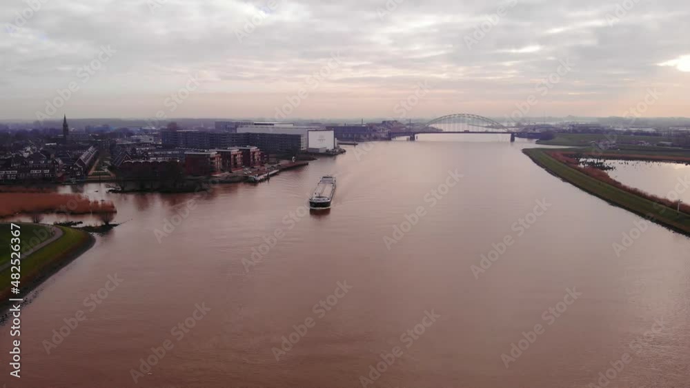 High Aerial View Over River Noord On Cloudy Day With Strelitzia Cargo Shop Passing Crezeepolder In Alblasserdam. Slow Pedestal down High Aerial View Over River Noord On Cloudy Day With Strelitzia Cargo Shop Passing Crezeepolder In Alblasserdam. Slow Pedestal down