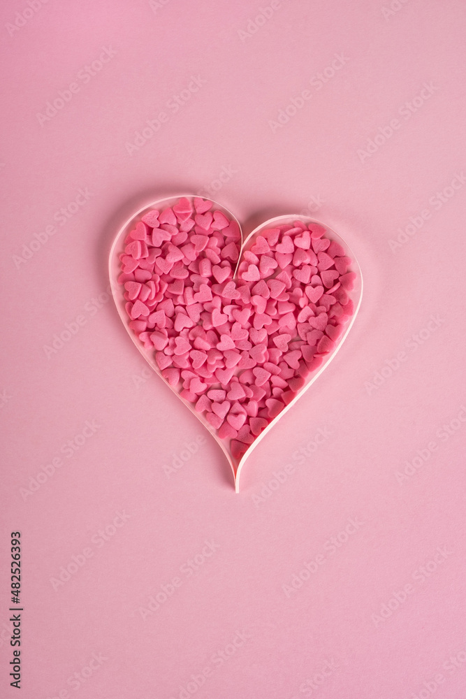 Valentines day composition. Sweet confetti shape of heart on pastel pink background. Top view, flat lay, vertical