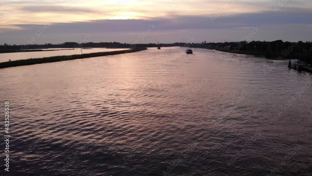 Aerial Sunset View Above River Noord Of Cargo Ship Travelling Past Crezeepolder Nature Reserve At Ridderkerk In Netherlands. Dolly Forward Aerial Sunset View Above River Noord Of Cargo Ship Travelling Past Crezeepolder Nature Reserve At Ridderkerk In Netherlands. Dolly Forward