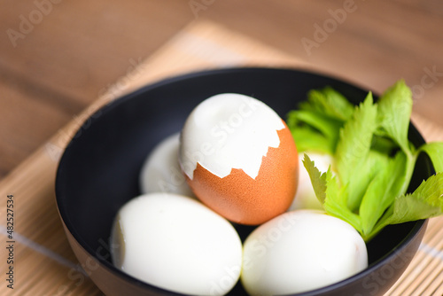 Eggs breakfast, fresh peeled eggs menu food boiled eggs in a bowl decorated with leaves green celery on wooden background, egg cooking healthy eating concept
