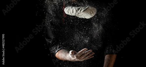 Fotografia flying pizza dough with flour scattering in a freeze motion of a cloud of flour midair on black