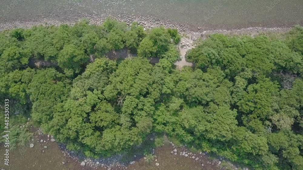 Narrow lush island drone ascend on top to reveal the water Narrow lush island drone ascend on top to reveal the water