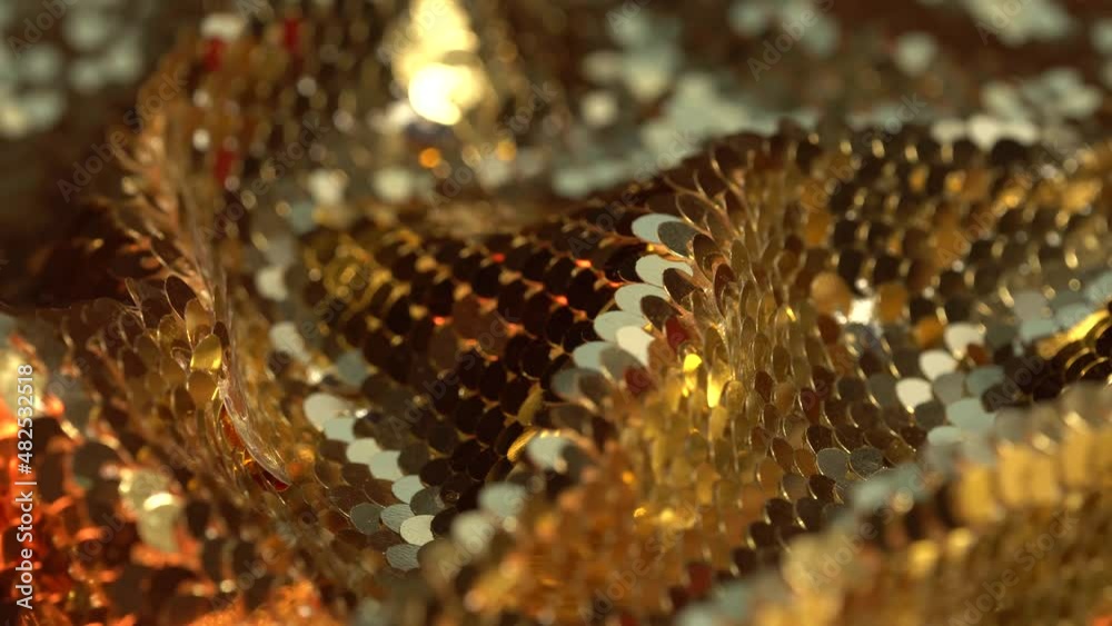 The texture of the fabric for a party with gold sequins close up. Neon colored lights and bokeh. Background for the holiday