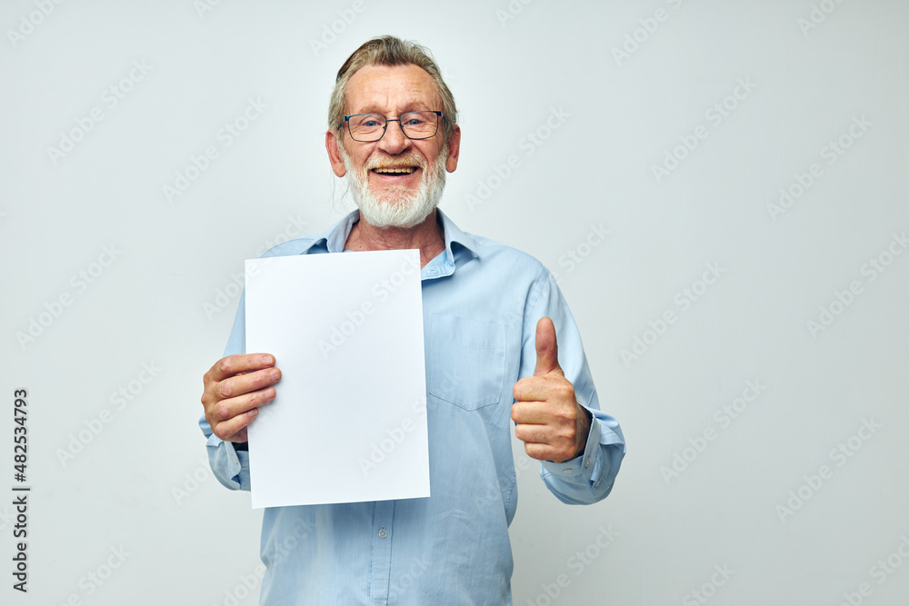 old man in a blue shirt and glasses a white sheet of paper light background old man in a blue shirt and glasses a white sheet of paper light background