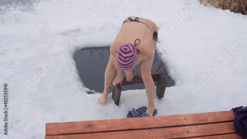 Winter swimming. Young woman dives into the cold water of the sea.