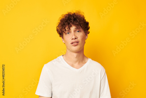 curly red-haired guy in a white t-shirt on a yellow background