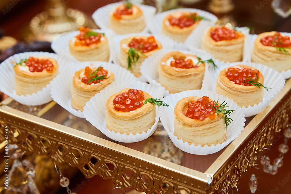 Snack at the buffet at the event. An assortment of snacks on a tray. Banquet service, restaurant on the road. Food, snacks with meat, ham, bread and tomatoes, seafood snacks, salmon, ham, caviar Snack at the buffet at the event. An assortment of snacks on a tray. Banquet service, restaurant on the road. Food, snacks with meat, ham, bread and tomatoes, seafood snacks, salmon, ham, caviar
