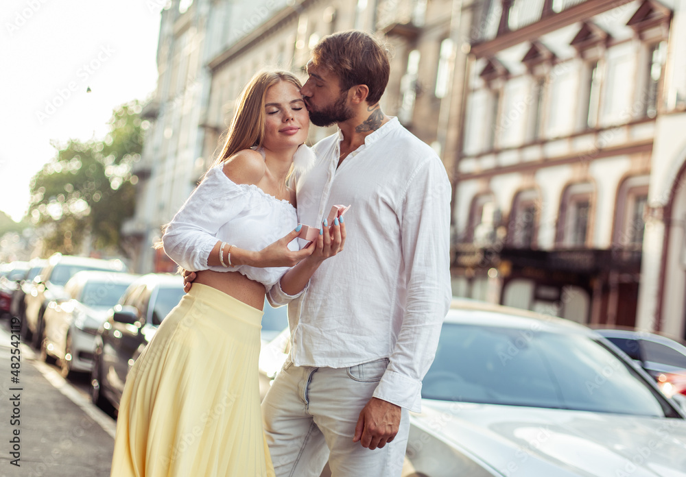Young man giving his woman gift in city. Couple in love, romantic concept Young man giving his woman gift in city. Couple in love, romantic concept