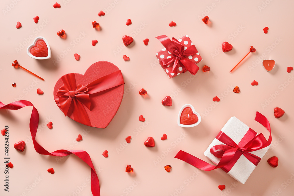 Valentines day composition with red decorations, candles, confetti and gifts on pink background. Happy greeting card. Top view. Flat lay
