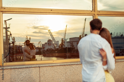 Young couple in love look at themselves in window reflection
