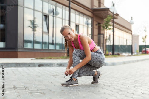 Fit woman tying shoelaces in the open air. Active lifestyle. Morning running
