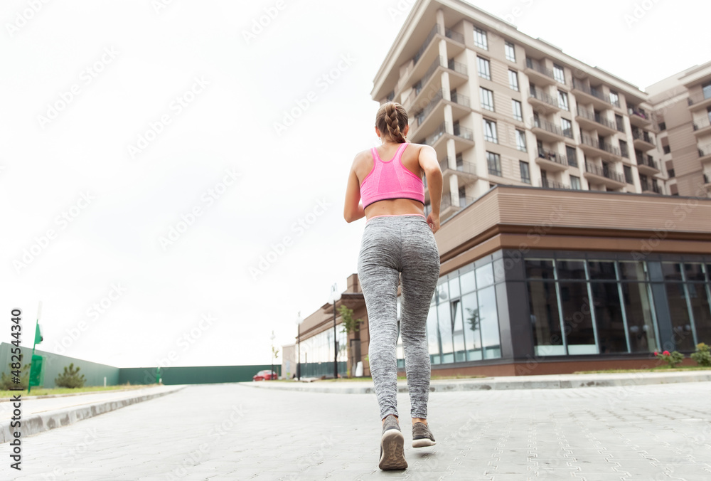 Fit woman practicing jogging near residential complex