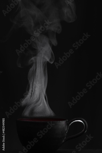 Steaming cup of tea with black background