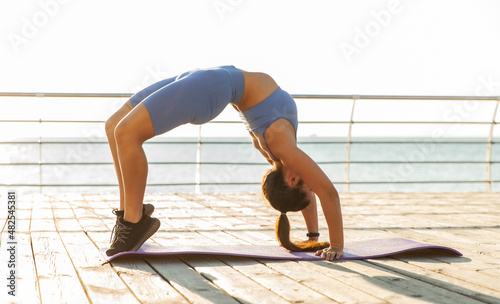 Fit woman practicing bridge exercise on the beach photo