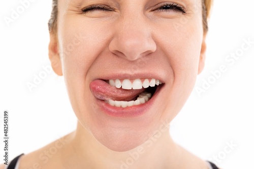close-up portrait of young woman with smile and tongue between teeth squint eyes and cheerful mood © Ivan Traimak