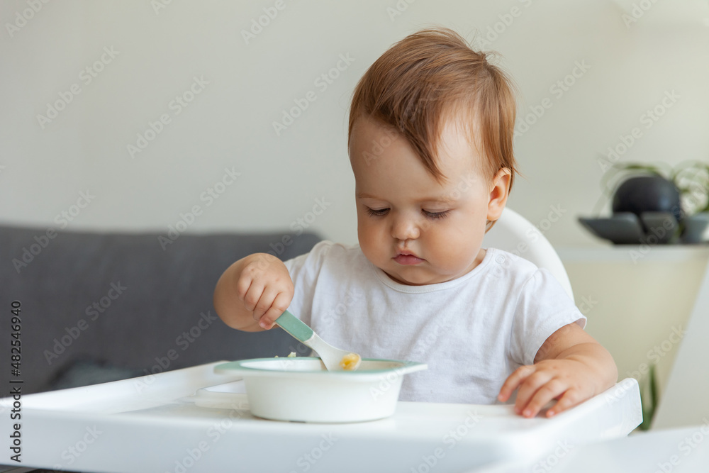 Little child eats while sitting at the children's table Little child eats while sitting at the children's table