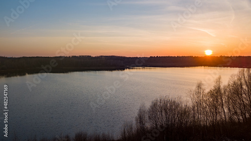 Aerial view shot by a drone of a beautiful dramatic and colorful sunset at coast of the lake. Nature landscape. Nature in Europe. reflection  blue sky and yellow sunlight. landscape during sunrise or