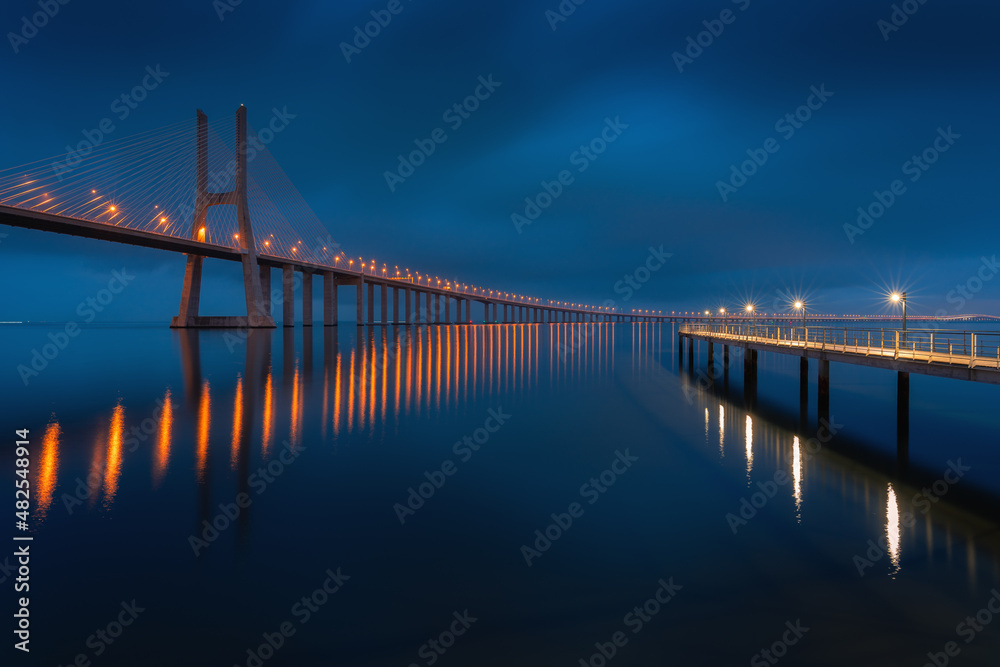 Fototapeta premium Moody cloudy long exposure image of Vasco Da Gama bridge on at night, long exposure fine art seascape.