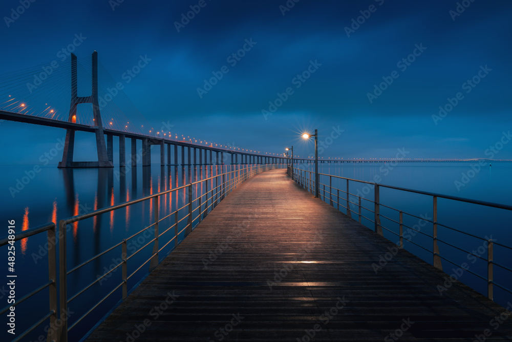 Moody cloudy long exposure image of Vasco Da Gama bridge on at night, long exposure fine art seascape.