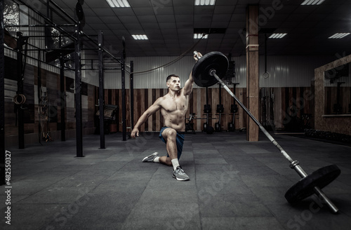 Athletic muscular man exercising with barbell in modern health club. Bodybuilding and Fitness