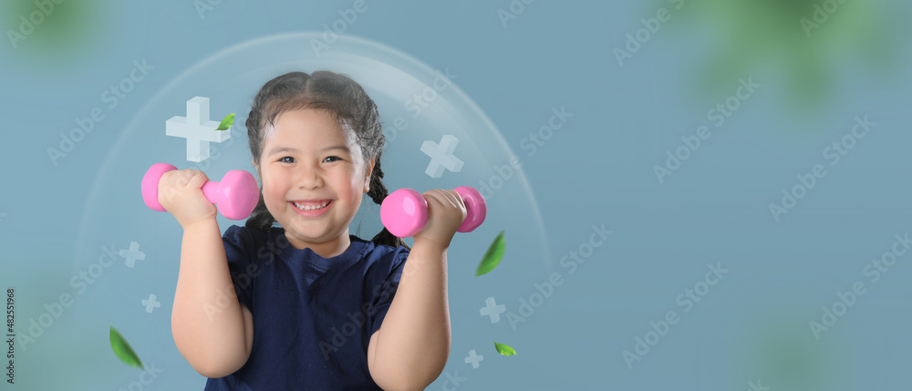Portrait of a healthy cute child girl playing dumbbell  isolated over blue background.