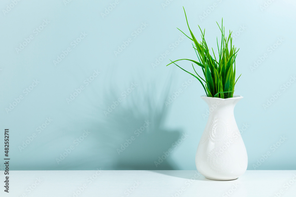 Green plant in a white vase on a green background Green plant in a white vase on a green background
