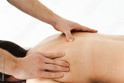 A male massage therapist in a blue suit makes a sports massage to a woman. Back pain treatment.