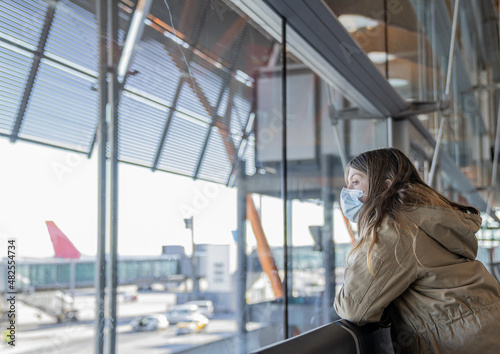 Young blonde Caucasian Girl looks at the planes from a window at the airport when travelling © Biddulph Photography