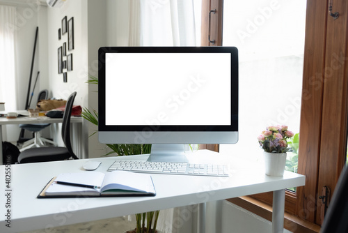 Blank screen desktop computer in office room with decorations and copy space