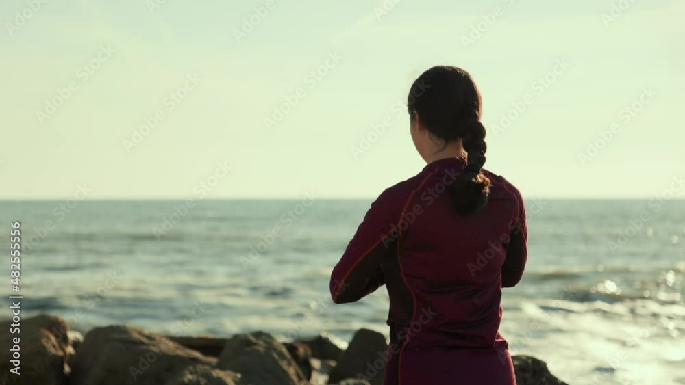 A woman meditates on the seashore. Back view. The sea surf is in the background. The concept of mental health and yoga. A woman meditates on the seashore. Back view. The sea surf is in the background. The concept of mental health and yoga.