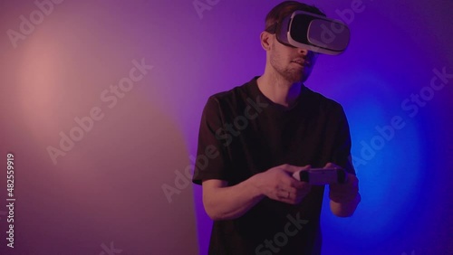 Man in metaverse using VR virtual reality glasses. Futuristic universe games and future in digital technology. Entreatment and NFT in neon colorful space. Happy male. Slow motion video in 3d cyber. photo