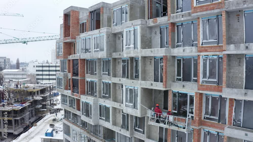 Aerial view of construction site in winter city. Building construction, construction industry. Construction workers on a building site with crane. Aerial view of construction site in winter city. Building construction, construction industry. Construction workers on a building site with crane.
