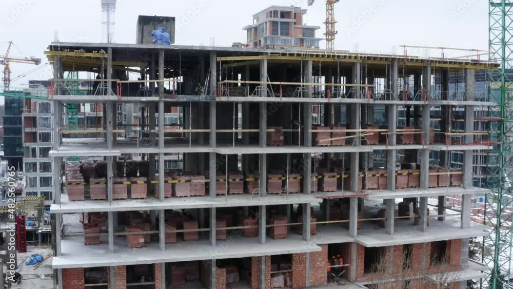 Aerial view of construction site in winter city. Building construction, construction industry. Construction workers on a building site with crane. Aerial view of construction site in winter city. Building construction, construction industry. Construction workers on a building site with crane.