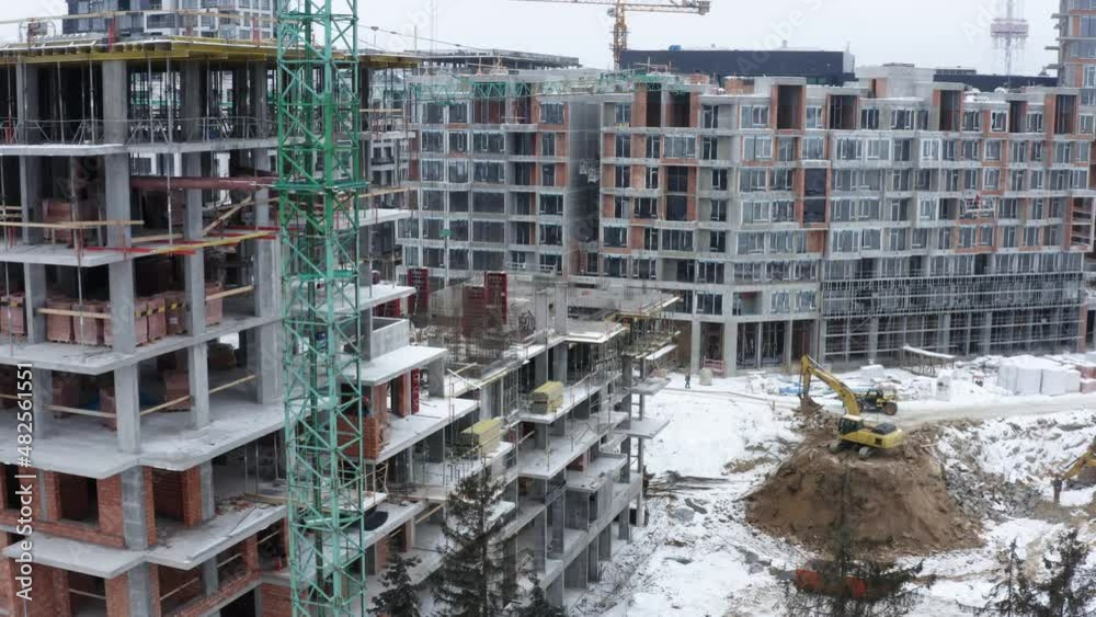 Aerial view of construction site in winter city. Building construction, construction industry. Construction workers on a building site with crane. Aerial view of construction site in winter city. Building construction, construction industry. Construction workers on a building site with crane.