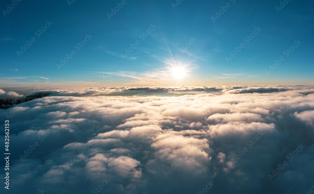 Sun shining brightly above white fluffy clouds at sunrise Sun shining brightly above white fluffy clouds at sunrise