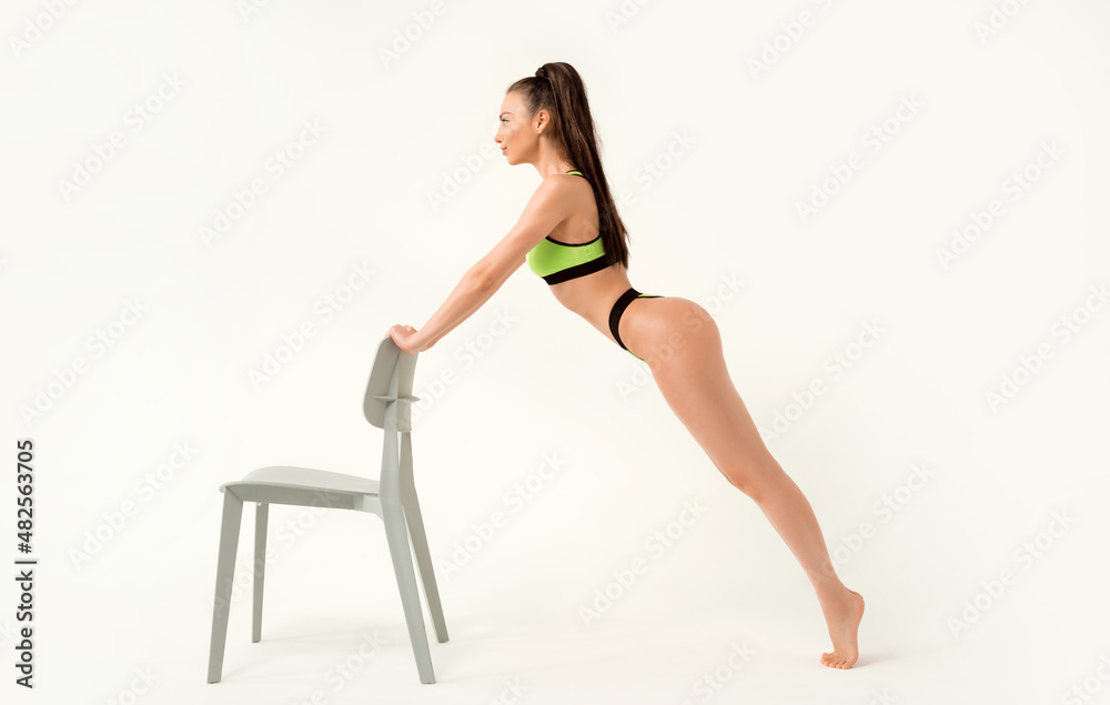 Attractive and sexy girl posing in the studio near the chair. Fashion photo of a beautiful athletic woman in green lingerie. Fitness concept. Attractive and sexy girl posing in the studio near the chair. Fashion photo of a beautiful athletic woman in green lingerie. Fitness concept.