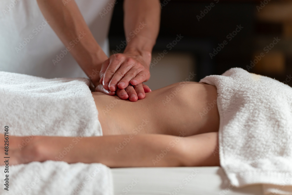 A masseuse woman doing an oil massage to another woman on the stomach A masseuse woman doing an oil massage to another woman on the stomach