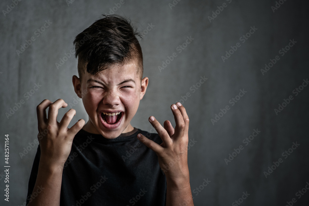 Teen boy screaming in anger on dark background. The problem of helping teenagers in a difficult period