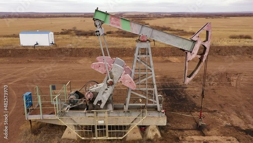 Pump jack in vast oil fields in Russia. Pipelines transporting oil from oil pumps, aerial drone shot