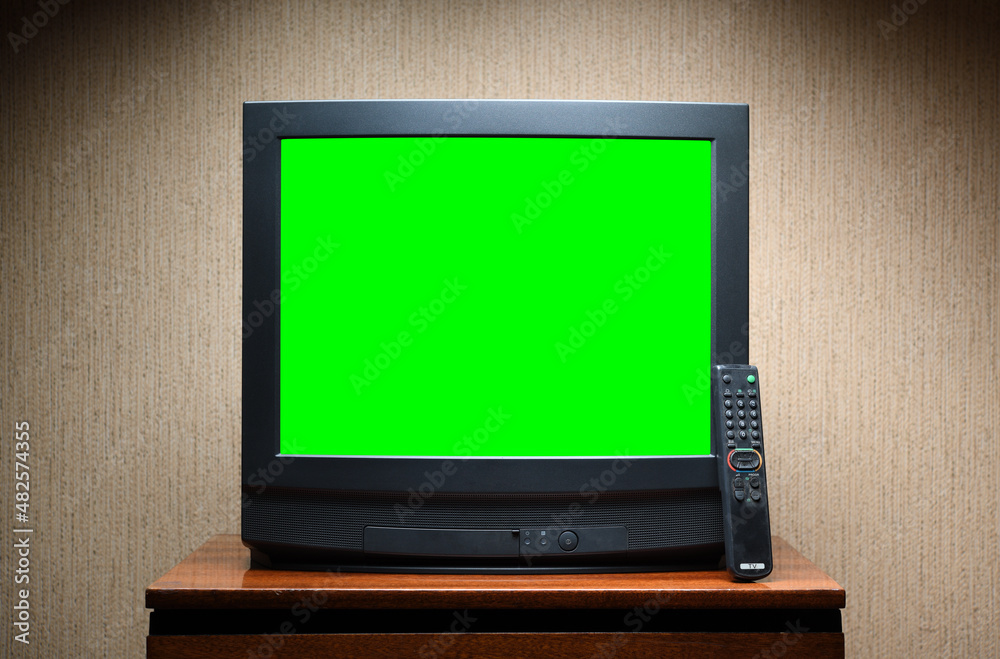 Antique TV with green screen on an antique wooden cabinet, old design in a house in the style of the 1980s and 1990s. Antique TV with green screen on an antique wooden cabinet, old design in a house in the style of the 1980s and 1990s.