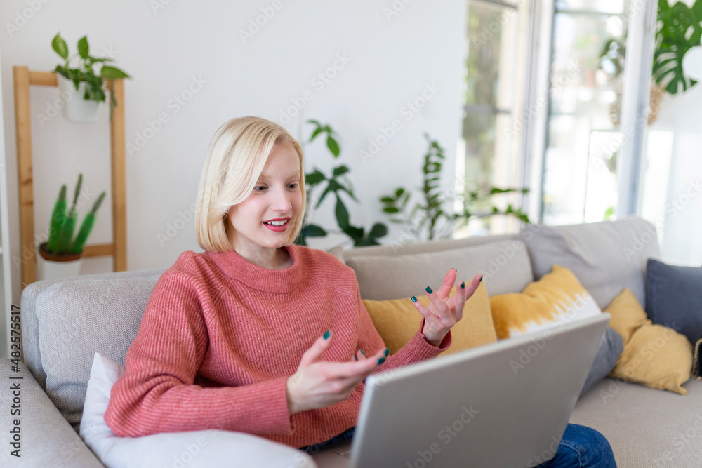 Smiling young woman using laptop at home, looking at screen, chatting, wearing wireless headset having video conference . business trainer tutoring by webcam, online training, e-coaching concept Smiling young woman using laptop at home, looking at screen, chatting, wearing wireless headset having video conference . business trainer tutoring by webcam, online training, e-coaching concept