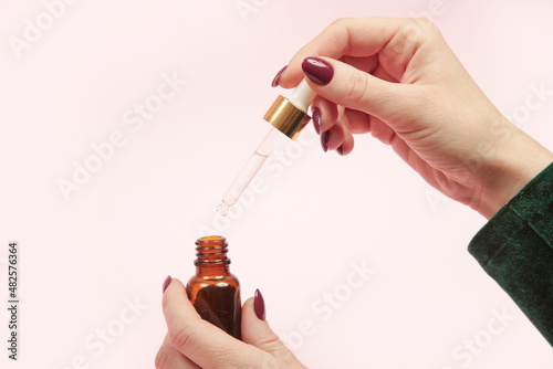 Hands hold pipette and dropper glass bottle with oil. Natural cosmetic, essentials oil, aromatherapy concept, skin care concept.