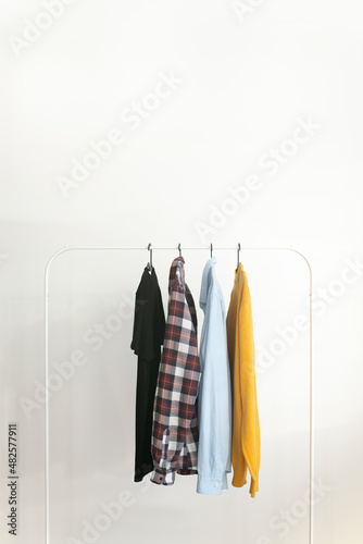 Rack with capsule clothes over white background Minimalism concept