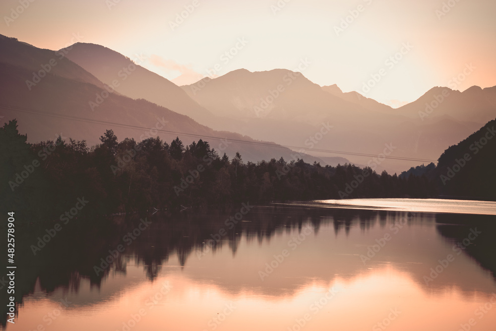 Dazzling sunset over the lake surrounded by forest and mountains
