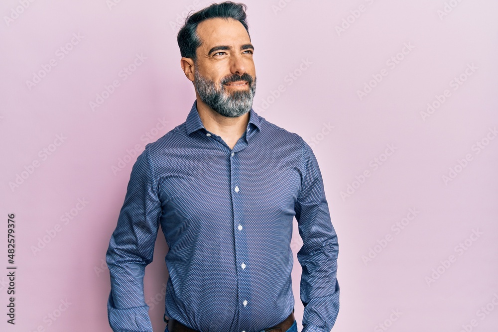 Obraz premium Middle age man with beard and grey hair wearing business clothes looking away to side with smile on face, natural expression. laughing confident.