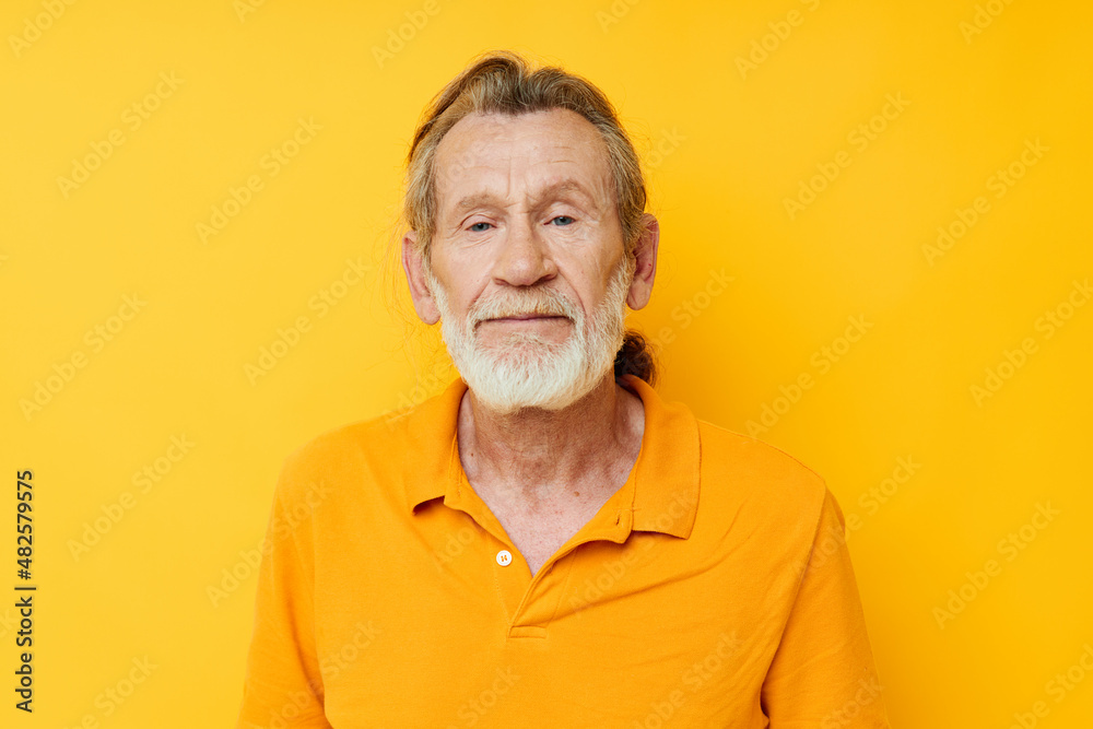 Obraz premium Portrait of happy senior man yellow shirt posing emotions yellow background